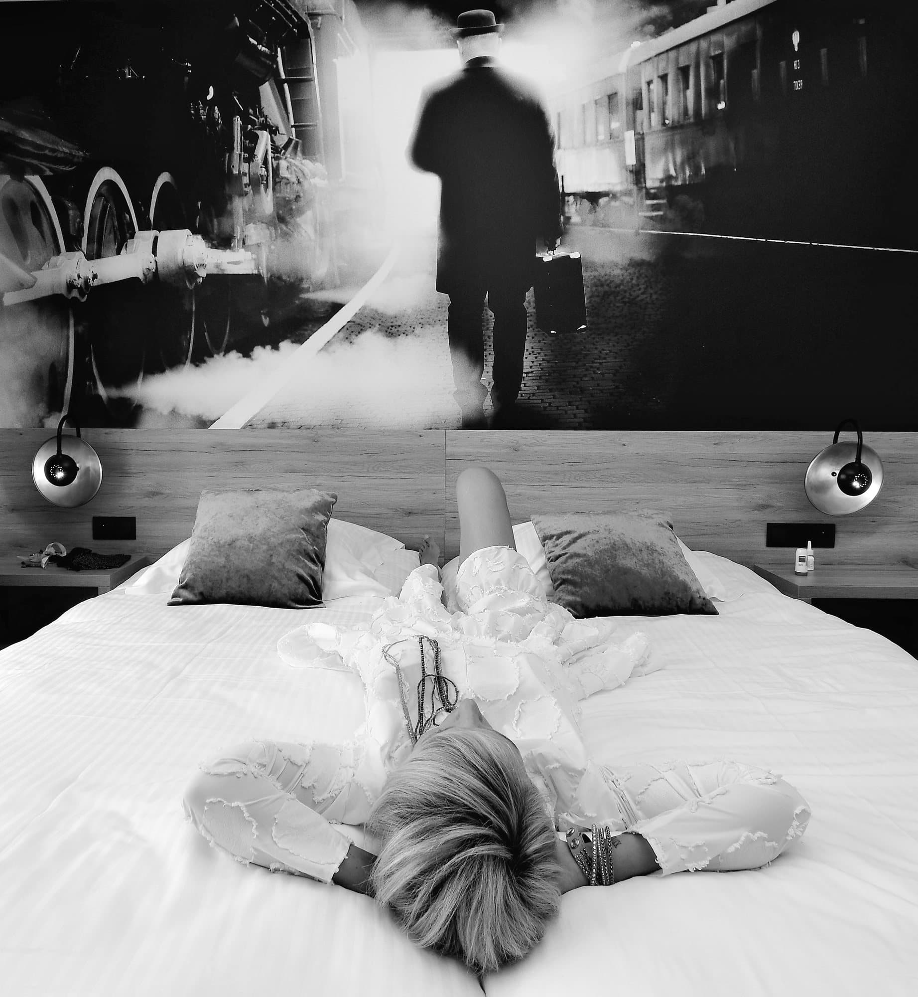 La mariée allongée sur le lit d'hôtel, sous une fresque de locomotive à vapeur