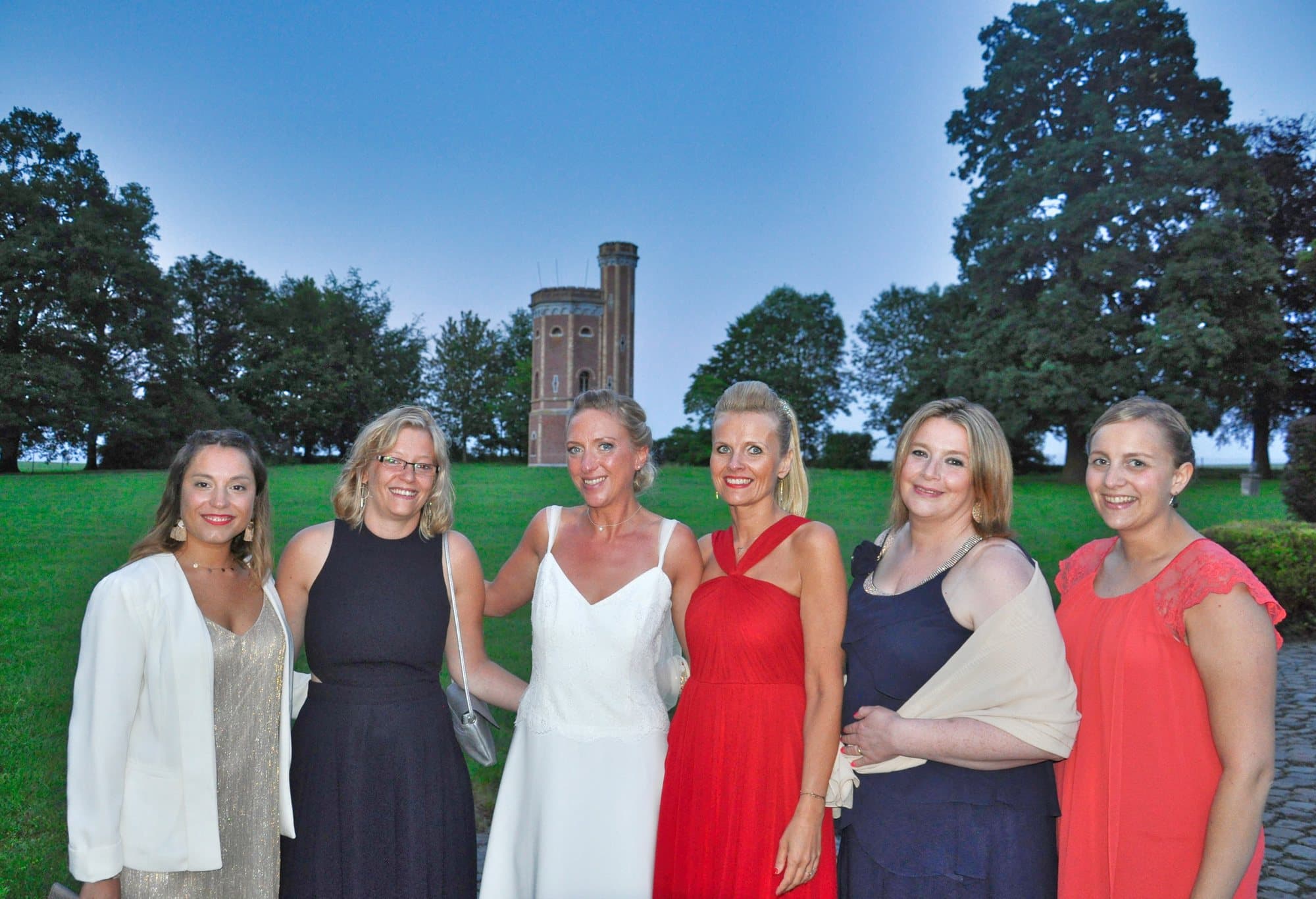 Six femmes dont la mariée au crépuscule devant la tour d'un château