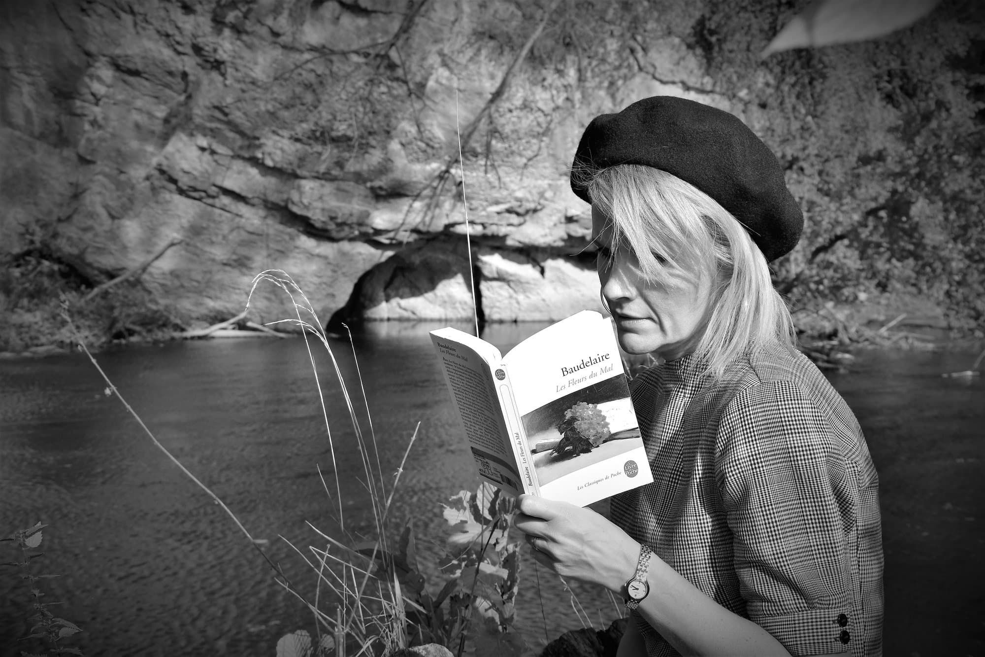 Femme en béret lisant Baudelaire au bord de l'eau