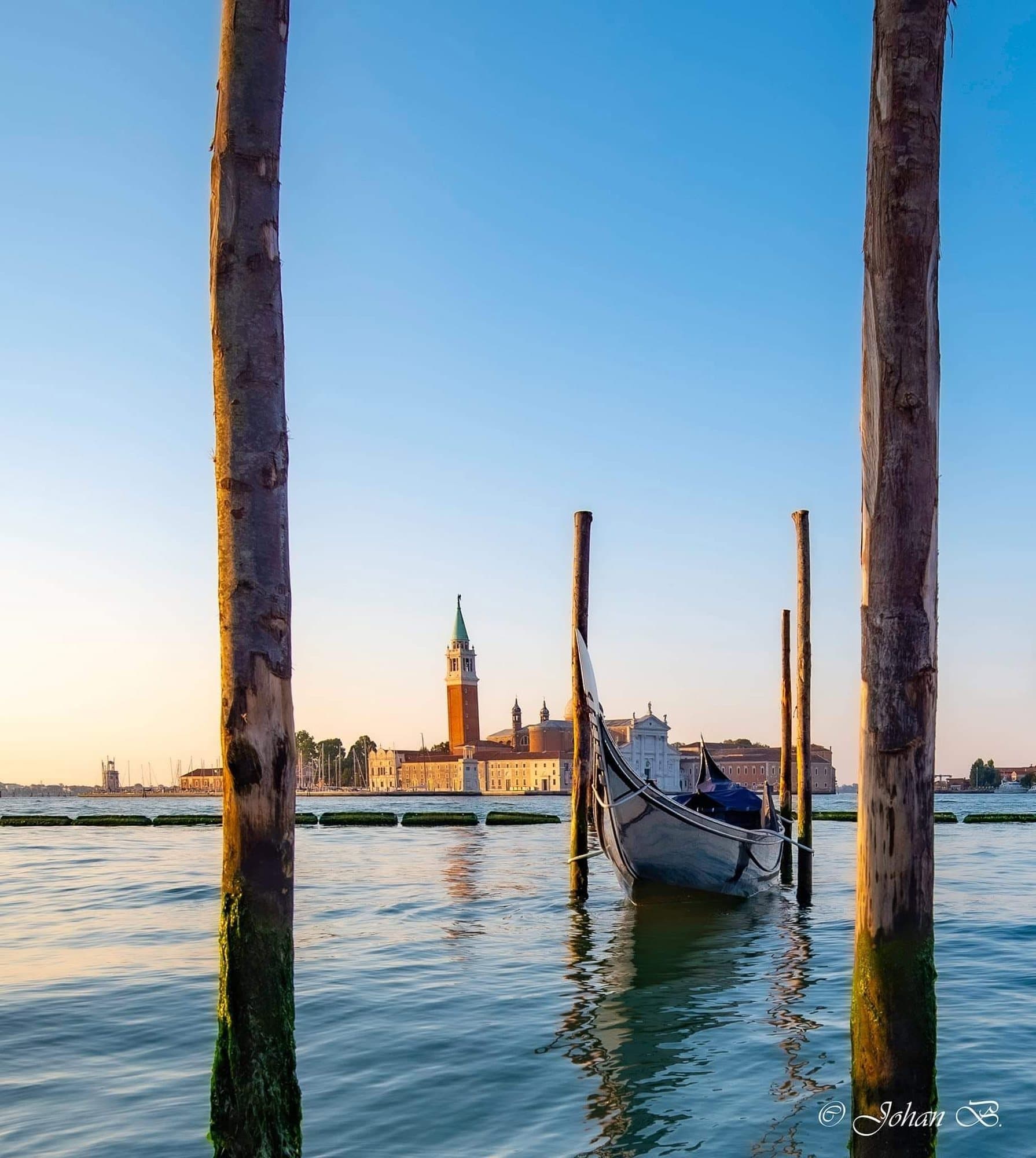 Gondole et basilique San Giorgio Maggiore à l'aube, entre les pieux d'amarrage