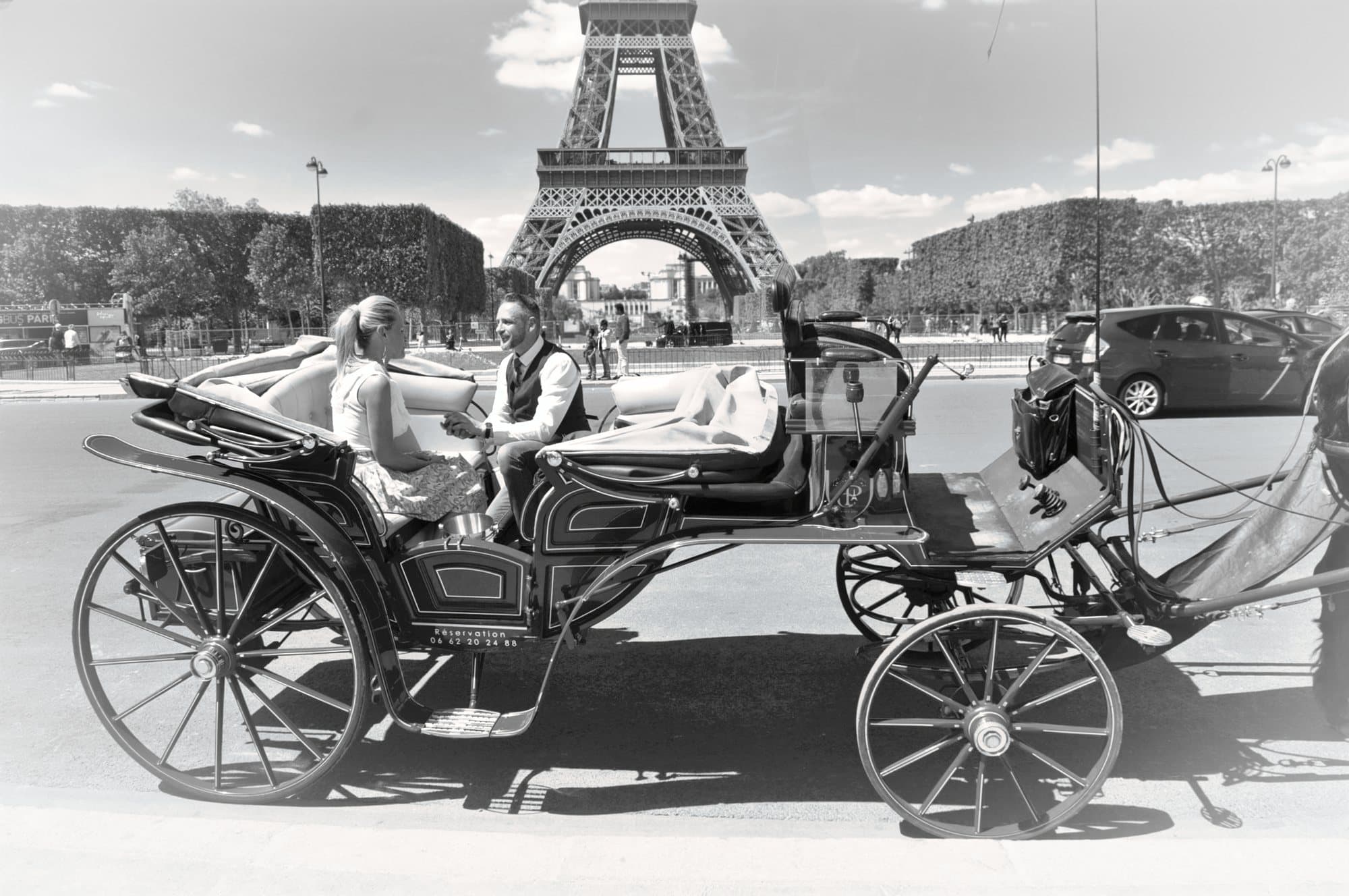 Couple assis dans une calèche, la tour Eiffel en arrière-plan