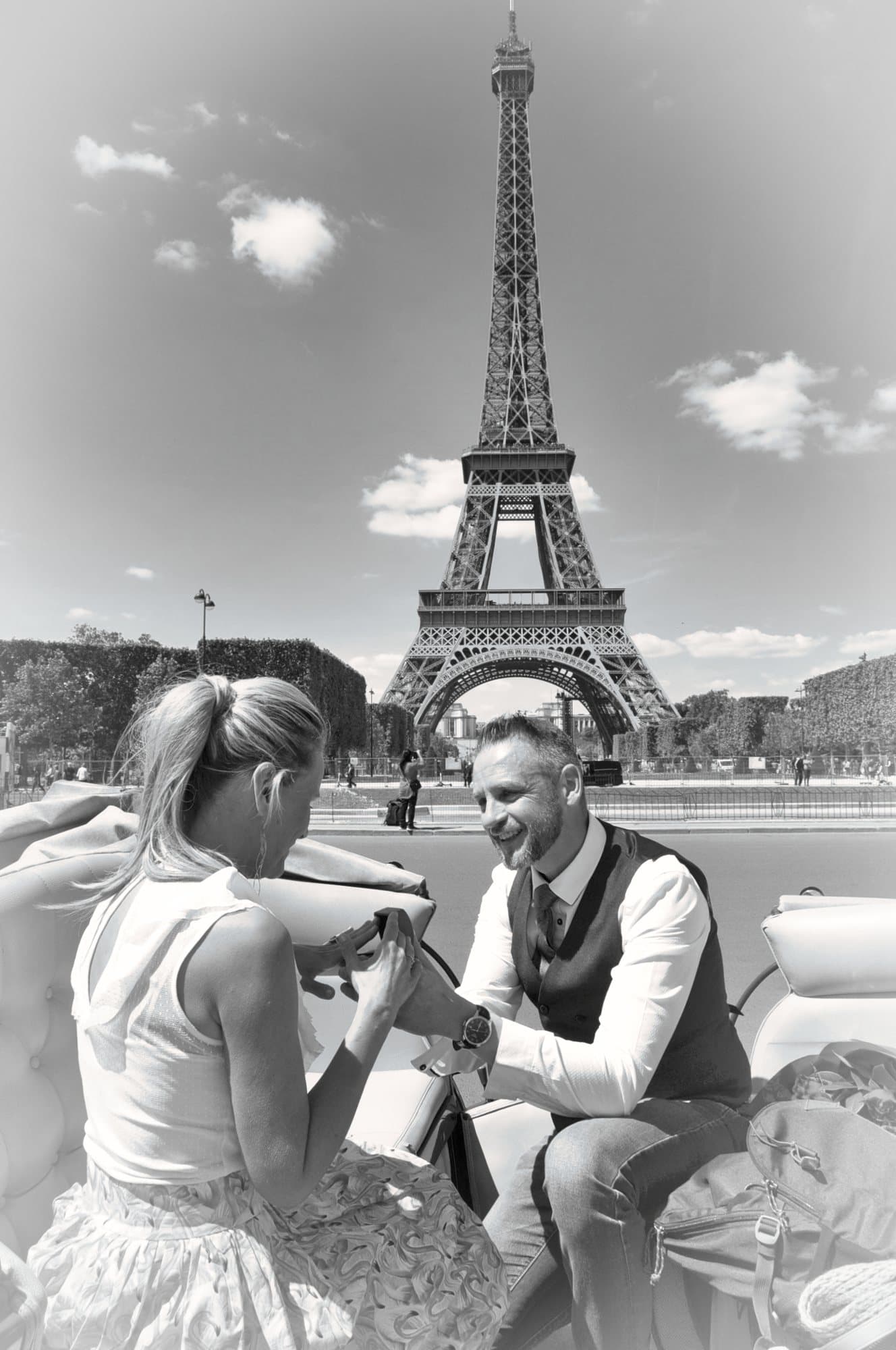 Mains des mariés échangeant l'alliance dans une calèche, la tour Eiffel au-dessus d'eux