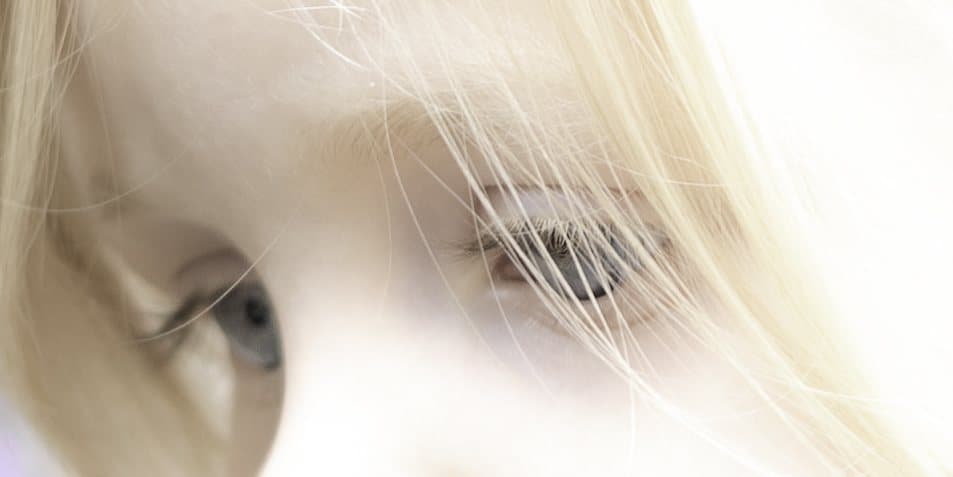 Très gros plan sur l'œil d'un enfant derrière une mèche blonde
