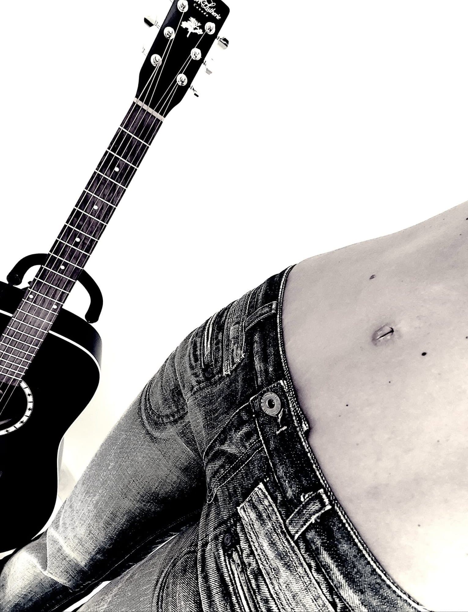 Guitare acoustique posée contre la taille et le jean d'une femme