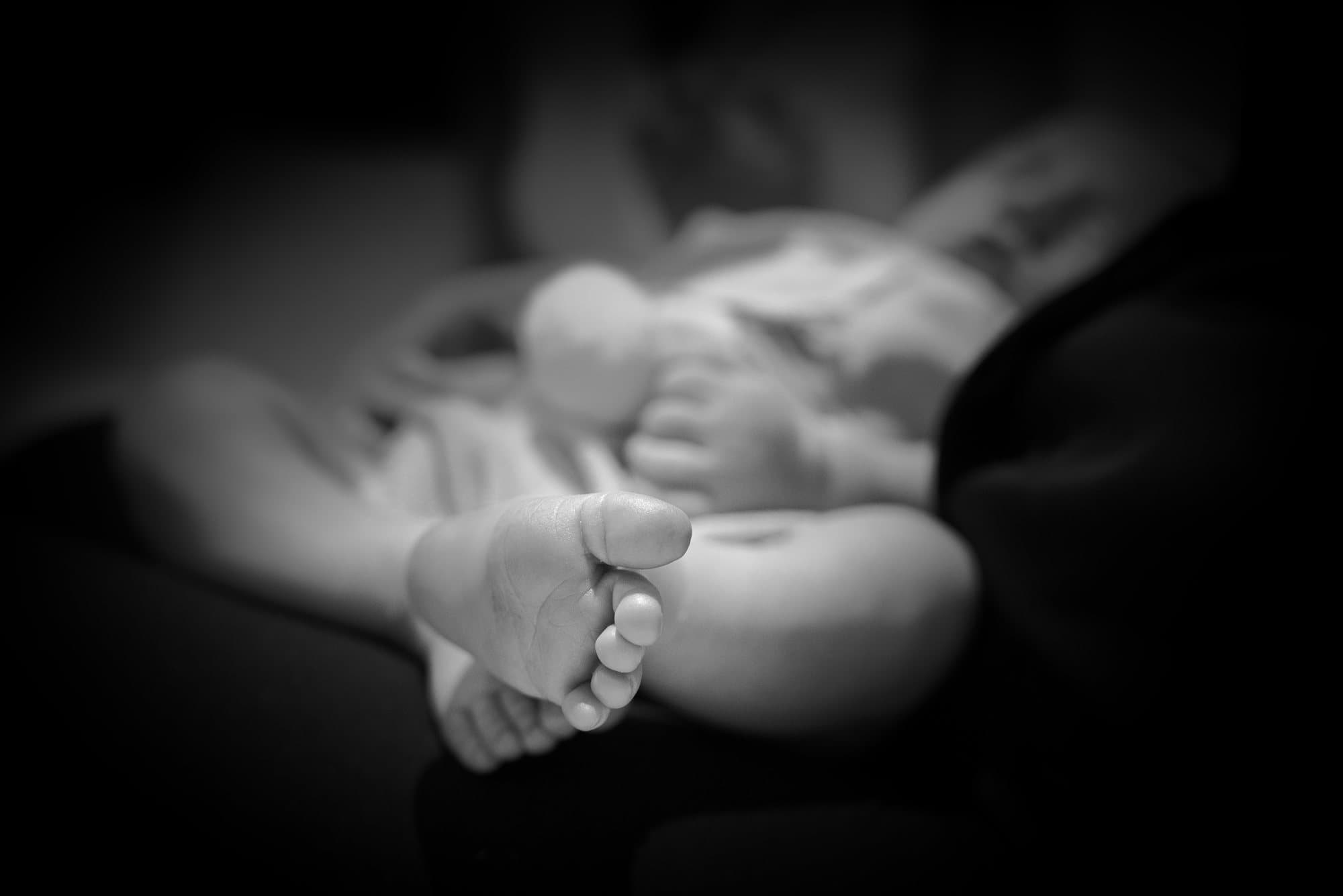 Pied de nouveau-né net au premier plan, le bébé endormi en arrière-plan