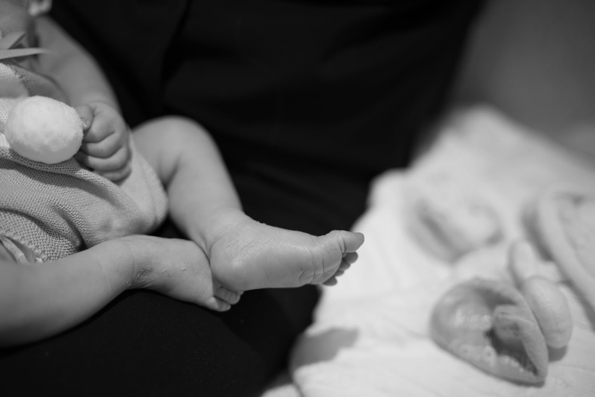 Jambes et pieds d'un nouveau-né en travers des genoux d'un parent